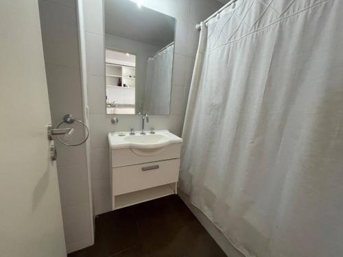 a white bathroom with a sink and a mirror at Studio Apartment on 13th Floor Above 9 de Julio Avenue in Buenos Aires