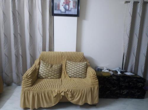 a yellow couch with two pillows in a room at Rent Room in Bashundhara R A near US Embassy in Dhaka