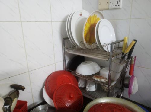 a pile of plates and dishes on a shelf in a kitchen at Rent Room in Bashundhara R A near US Embassy in Dhaka