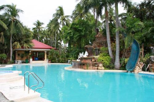 a swimming pool with a fountain in a resort at San Remigio Beach Club in San Remigio