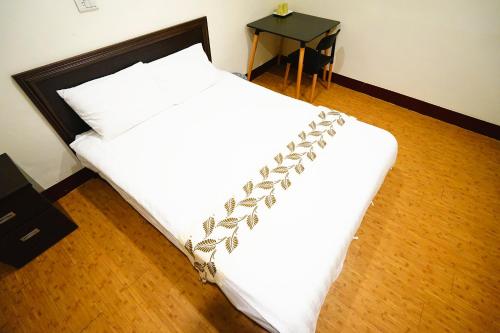1 dormitorio con 1 cama blanca con manta blanca en 尋 清芳民宿 瑞芳車站-九份 平溪 en Ruifang