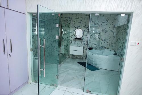 a bathroom with a glass shower and a tub at Elegant and Cosy Four Bedroom Home in Accra in Accra