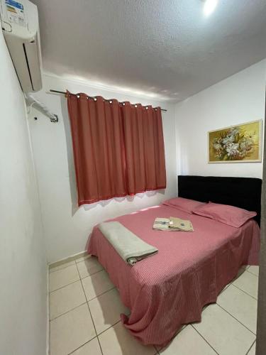 a bedroom with a pink bed with a red curtain at Onix Sol e Piscina in Campos dos Goytacazes