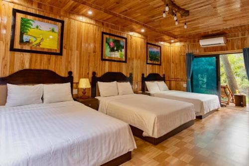 two beds in a room with wooden walls at Hang Lan Bungalow in Ninh Binh