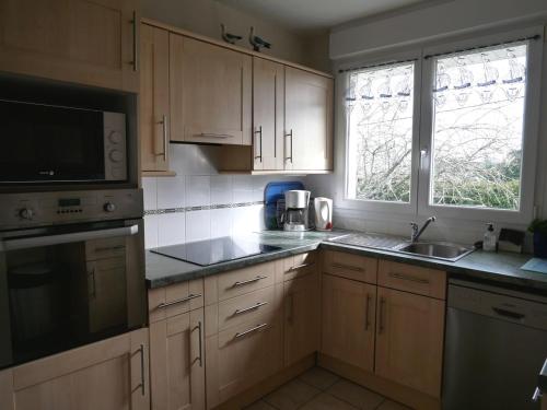 La cuisine est équipée de placards en bois, d'un évier et d'un four micro-ondes. dans l'établissement Maison de vacances à Sarzeau, entre plages et golfe, calme et bien équipée - FR-1-639-27, à Sarzeau