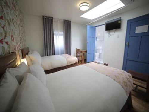 a bedroom with two white beds and a television at Posada Villa Mayor in Cusco