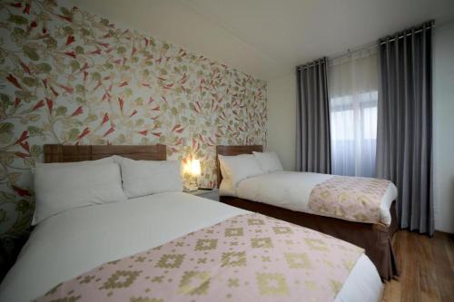 two beds in a hotel room with floral wallpaper at Posada Villa Mayor in Cusco