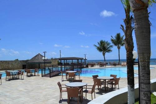 a resort with tables and chairs next to a swimming pool at Muro Alto Marupiara Suítes in Porto De Galinhas