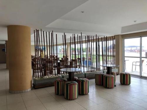 a room with three tables and chairs and a room with windows at Muro Alto Marupiara Suítes in Porto De Galinhas