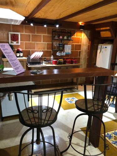 a kitchen with a counter with two chairs and a table at Casa de Praia - meu lugar em Iriri in Anchieta
