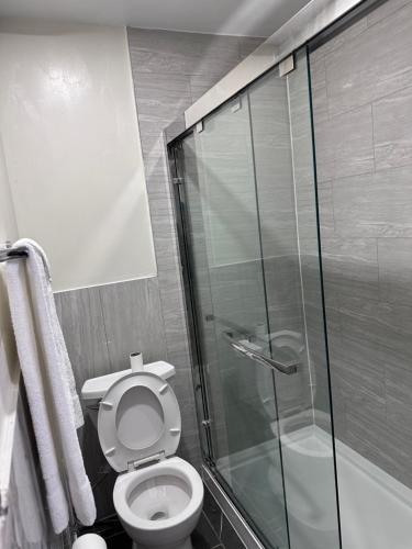 a bathroom with a toilet and a glass shower at Cedar Springs Motel in Acton
