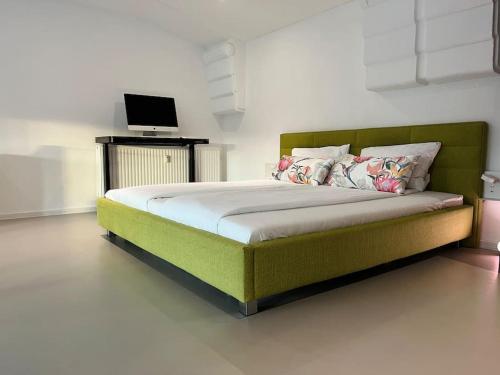 Schlafzimmer mit einem grünen Bett und einem Laptop auf dem Schreibtisch in der Unterkunft Duplex Loft mit Garten in Magdeburg