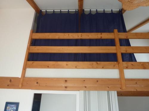 ein Etagenbett aus Holz in einem Zimmer mit einem blauen Vorhang in der Unterkunft Maison Bretignolles-sur-Mer, 1 pièce, 5 personnes - FR-1-231-295 in Brétignolles-sur-Mer