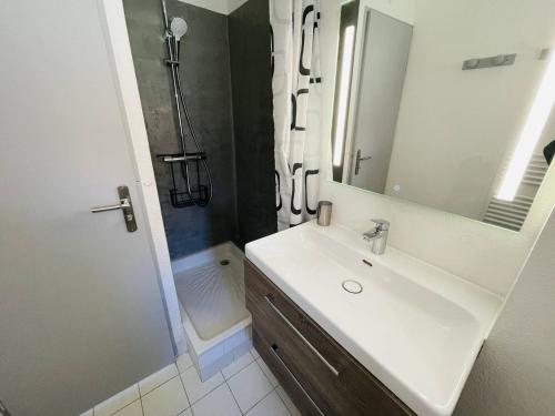 une salle de bain avec un lavabo, une douche et un miroir dans l'établissement Appartement avec piscine, tennis, clim, parking et wifi au Cap d'Agde - FR-1-723-118, au Cap d'Agde