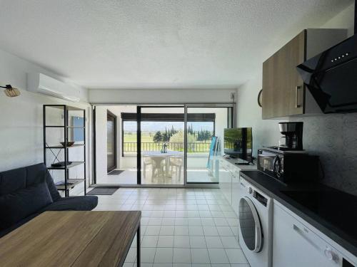 Il comprend une cuisine et un salon avec une table. dans l'établissement Appartement avec piscine, tennis, clim, parking et wifi au Cap d'Agde - FR-1-723-118, au Cap d'Agde