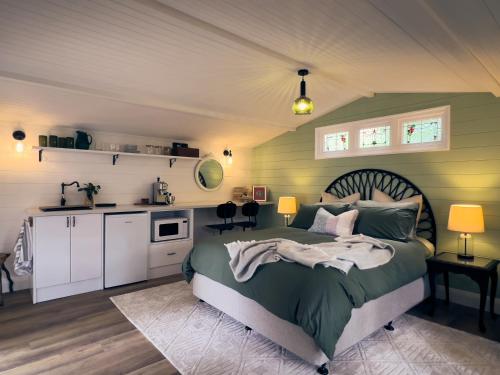 a bedroom with a green bed and a kitchen at Bundanoon Garden Retreat in Bundanoon