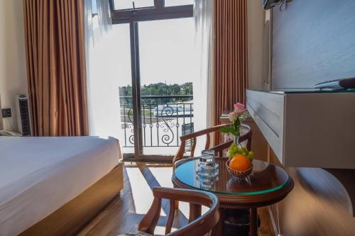 um quarto de hotel com uma cama e uma mesa com fruta em Win Hotel Đà Lạt em Da Lat
