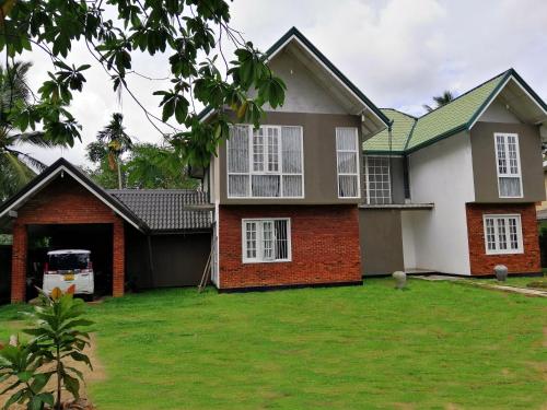 uma casa com um relvado verde em frente em Five Bed two-storey luxury House in 44 perch land in Bandaragama, Sri Lanka em Bandaragama