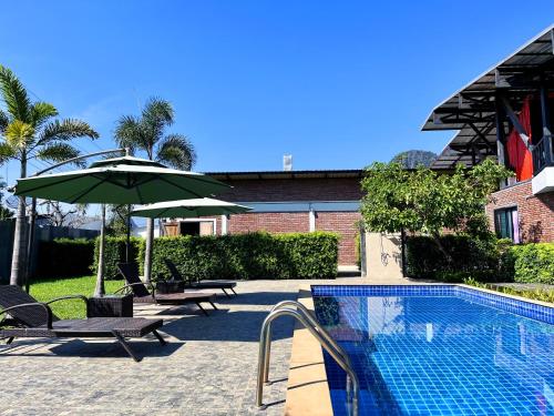 a pool with two chairs and an umbrella and a table and chairs sidx sidx sidx at Hailin Resort Vangvieng in Vang Vieng
