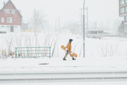 a person walking in the snow with a snowboard at MUWA NISEKO in Kutchan