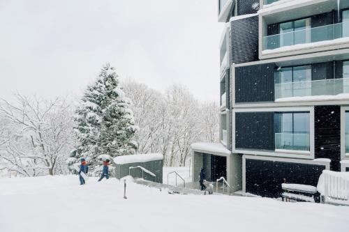 two people walking in the snow in front of a building at MUWA NISEKO in Kutchan