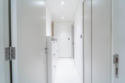 a white kitchen with a hallway with a mirror at FIRST CLASS 3BR with Dubai Marina & Palm View in Dubai