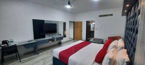 Dormitorio con cama, escritorio y TV en Hotel krishna en Nizāmābād