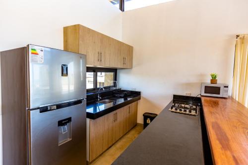a kitchen with a stainless steel refrigerator and wooden cabinets at Casa Macondo - Casa de playa en Vichayito by WiroHouse in Vichayito