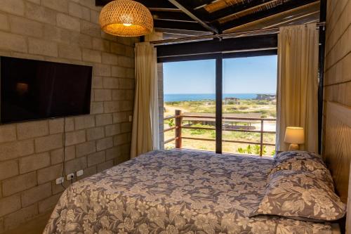 a bedroom with a bed and a large window at Macondo, casa de playa en Vichayito by WiroHouse in Vichayito