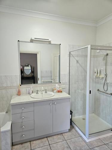 een badkamer met een wastafel, een douche en een spiegel bij Gungurru in Corowa
