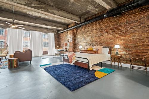 a bedroom with a bed and a brick wall at Charming Boho Loft on Historic Morris Ave in Birmingham