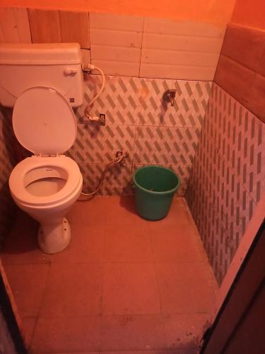 a bathroom with a toilet and a green bucket at Shivalik guest house in Dhanaulti