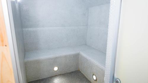 a walk in shower with white tiled walls and a shower at Eco hotel & restaurant "SKALA" in Borovoye
