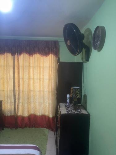 a room with a curtain and a table with a window at Jamaican J Home in Kingston
