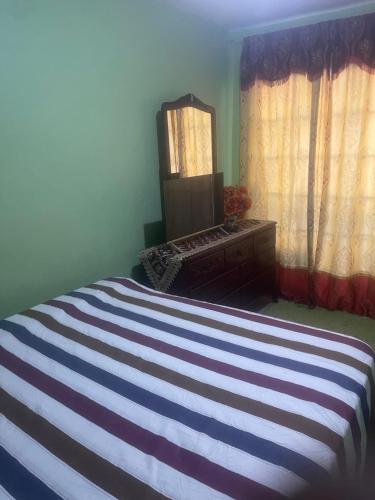 a bedroom with a bed with a mirror and a dresser at Jamaican J Home in Kingston