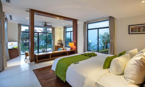 a bedroom with a large white bed and large windows at Cam Ranh Riviera Beach Resort & Spa in Cam Ranh