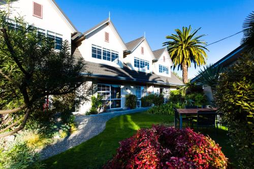 a large white house with a palm tree in the yard at ASURE Colonial Lodge Motel in Napier