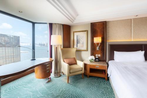 a hotel room with a bed and a desk and a window at Kowloon Shangri-La, Hong Kong in Hong Kong