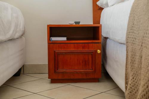 a small wooden night stand next to a bed at Broadway Boston in Cape Town
