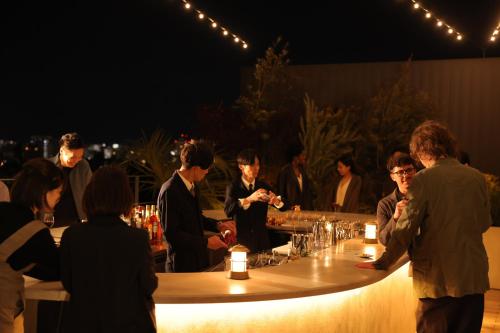 un grupo de personas de pie alrededor de un bar por la noche en NOHGA HOTEL KIYOMIZU KYOTO en Kyoto