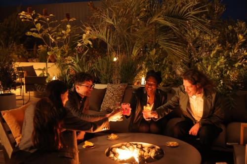 a group of people sitting around a table in front of a fire at NOHGA HOTEL KIYOMIZU KYOTO in Kyoto