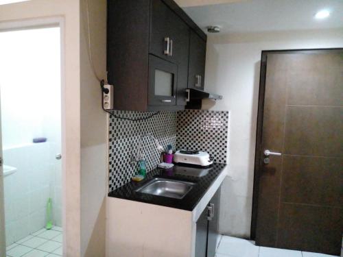 a small kitchen with a sink and a microwave at GREENROOM Apartemen Bogor Valley in Kalibata 1