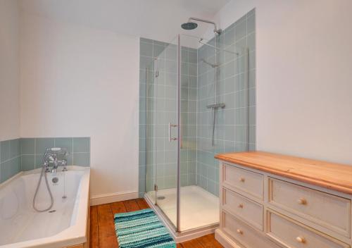 a bathroom with a shower and a tub and a sink at Oswalds Cottage in Dinas Mawddwy