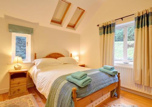 a bedroom with a bed with two towels on it at Oswalds Cottage in Dinas Mawddwy