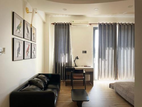a living room with a couch and a table and a desk at Nhà mình Homestay in Rach Gia