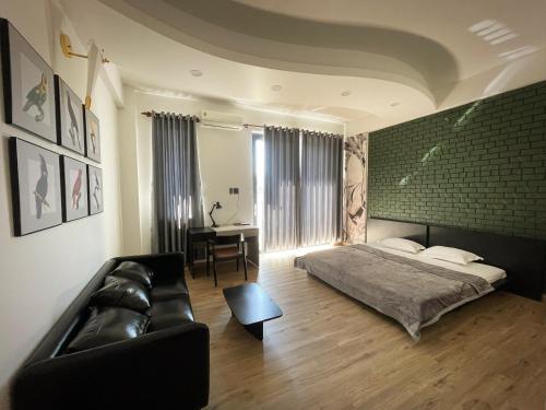 a bedroom with a bed and a couch and a table at Nhà mình Homestay in Rach Gia