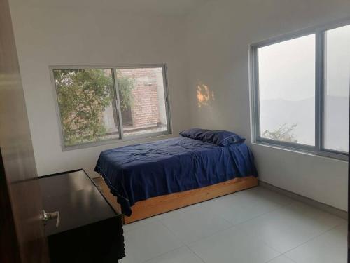 ein Schlafzimmer mit einem Bett und zwei Fenstern in der Unterkunft Villa Campestre con vista in Guadalajara