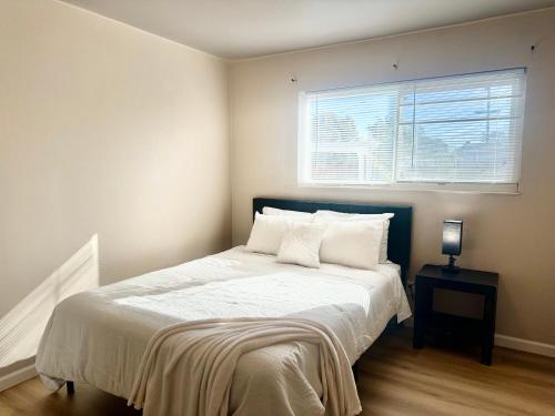 a bedroom with a bed with white sheets and a window at 10% off! Chic Home with Expansive Backyard in San Mateo