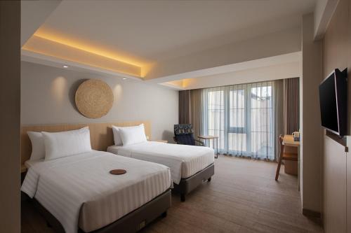 a hotel room with two beds and a television at Aveta Hotel Malioboro in Yogyakarta