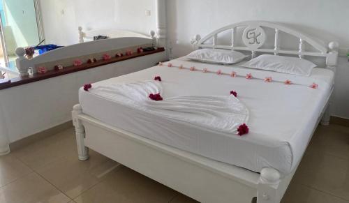 una camera con due letti bianchi con fiori rossi di New Casamarc a Bentota